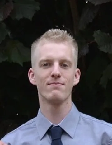 Porträt von Joshua Bloch, Koch EFZ und Sous-Chef aus der Region Olten und Solothurn, mit ruhigem, direktem Blick in die Kamera vor natürlichem grünem Hintergrund.